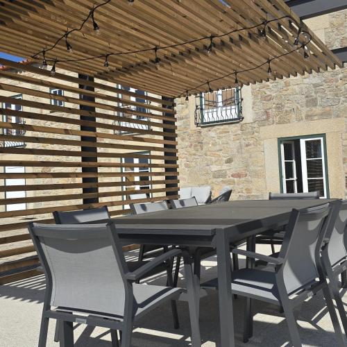 a black table and chairs under a wooden pergola at Casa da Fidalga in Outeiro de Gatos