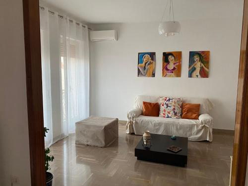 a living room with a couch and paintings on the wall at OLIVIA e TETI in Santeramo in Colle