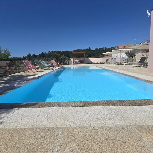 a large blue swimming pool with chairs in the background at Casa da Fidalga in Outeiro de Gatos