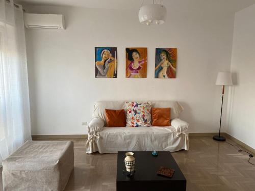 a living room with a couch and paintings on the wall at OLIVIA e TETI in Santeramo in Colle
