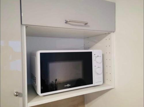un four micro-ondes assis sur une étagère dans un mur dans l'établissement S2 Bel appartement 10min centre Paris stade de France, à Saint-Denis