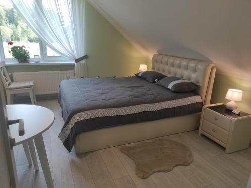 a bedroom with a bed and a table and a window at Viesu nams Sampale in Ķeipene