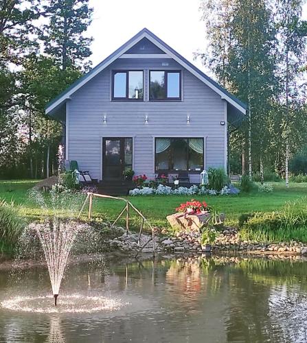 a house with a fountain in the middle of a pond at Viesu nams Sampale in Ķeipene