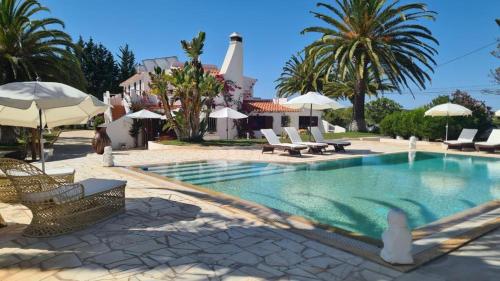 a pool with chairs and umbrellas next to a house at RÉSIDENCE LES ARCADES in Almádena