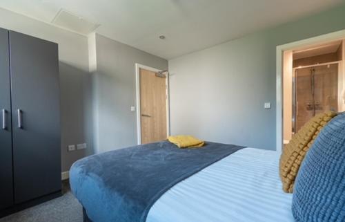 a bedroom with a blue bed with a yellow pillow on it at Two bedroom Newcastle City Quayside Apartment in Newcastle upon Tyne