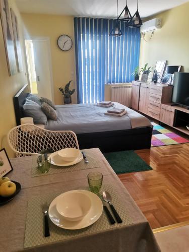 a bedroom with a bed and a table with plates on it at Green Apple Apartment in Subotica