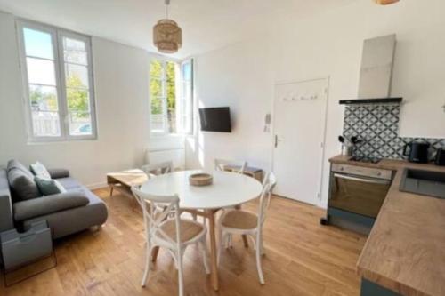 un salon avec une table et une cuisine dans l'établissement La Corderie - Appartement sur le Quai aux Vivres, à Rochefort