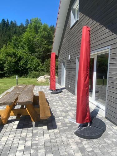 a picnic table and two red poles in front of a building at La cabane des écureuils in Xonrupt-Longemer