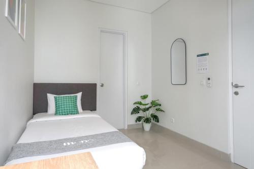 a white bedroom with a bed and a plant at Mono Coliving at BSD City in Tegal
