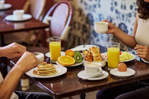 a group of people sitting at a table eating breakfast at Hotel Le Grimaldi by Happyculture in Nice
