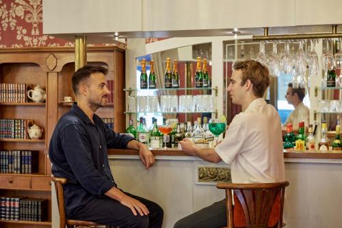 a man and a woman sitting at a bar at Hotel Le Grimaldi by Happyculture in Nice