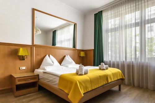 a bedroom with a large bed with a yellow blanket at Hotel Corvinus Vienna in Vienna