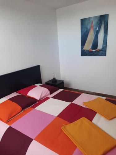 a bedroom with a large bed with colorful sheets and pillows at Duplex avec vue sur mer-La Rose des Vents in Saint-Côme-de-Fresné