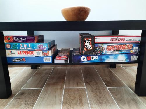 a shelf full of games on a table at Duplex avec vue sur mer-La Rose des Vents in Saint-Côme-de-Fresné