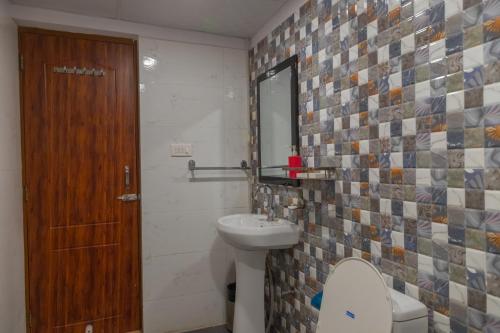 a bathroom with a toilet and a sink and a mirror at Hotel Sethi Legacy in Haridwār