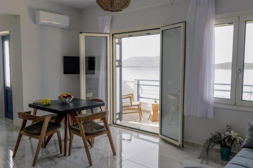 a dining room with a table and chairs and a balcony at Grand Bleu Apartments & Villas in Ermioni