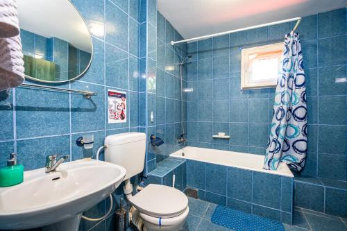 a blue tiled bathroom with a toilet and a sink at Breazary in Breaza de Jos