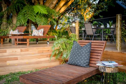a wooden bench with a pillow on a patio at Sunbirds Oasis Lodge in Hoedspruit