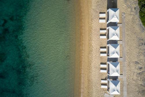 - une vue sur la plage avec une rangée de chaises blanches dans l'établissement Princess Resort, Santikos Collection, à Agia Paraskevi