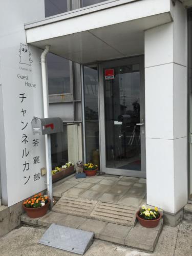 an entrance to an office building with flowers in pots at Guesthouse Channel-Kan in Kamojima