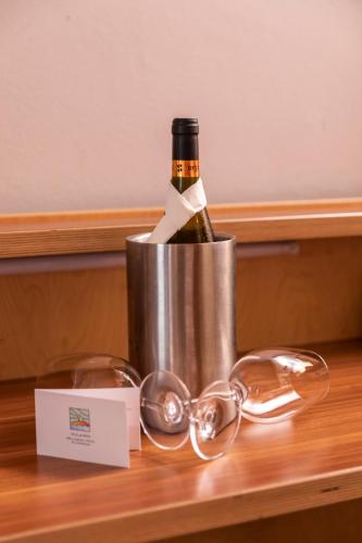 a bottle of wine in a bucket with glasses on a table at Vulkán Wellness Hotel & Camping in Celldömölk