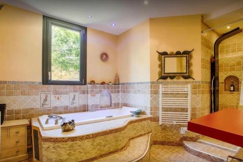 La grande salle de bains est pourvue d'une baignoire et d'une fenêtre. dans l'établissement Le Manoir du Val, à Douvres-la-Délivrande