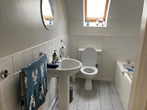 a white bathroom with a sink and a toilet at Grovehouse in Portstewart