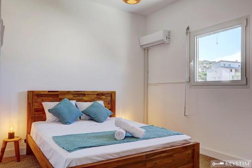 a bedroom with a bed with blue pillows and a window at Villa Haven - Piscine - Grand-Bois in Saint-Pierre