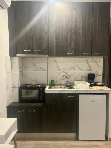 a kitchen with wooden cabinets and a sink and a microwave at Cinque Stelle Apartments in Glífa