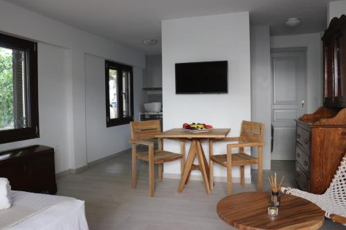 a living room with a table and chairs and a tv at Grand Bleu Apartments & Villas in Ermioni