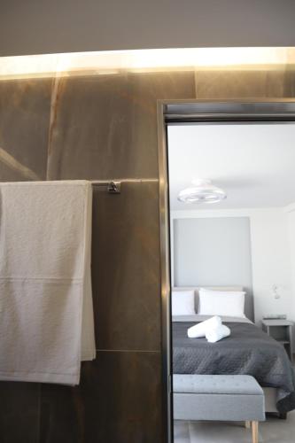 a bedroom with a bed and a glass door with a shower at Golden Sand Suites in Anavissos