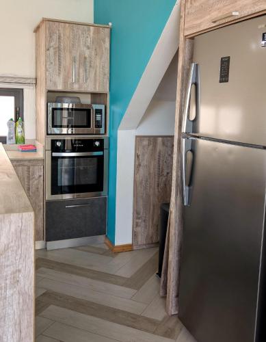 a kitchen with a stainless steel refrigerator and wooden cabinets at Maison des Sables/Pano in Pointe aux Sable