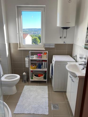 a bathroom with a toilet and a sink and a window at Apartment Bumbar Sunset in Rogoznica