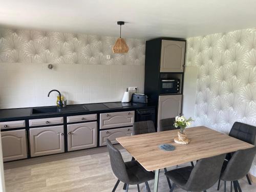 une cuisine avec une table en bois, des chaises et une table. dans l'établissement La maison de Cécile, à Vallières