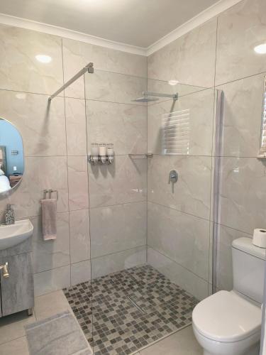 a bathroom with a shower with a toilet and a sink at Mabalel Lodge in Nelspruit
