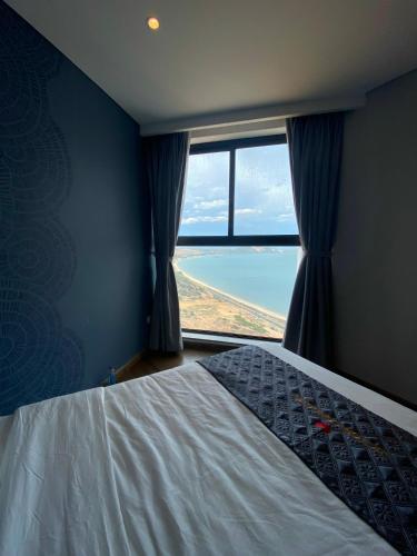 a bedroom with a bed and a large window at APEC Mandala Mũi Né in Mui Ne