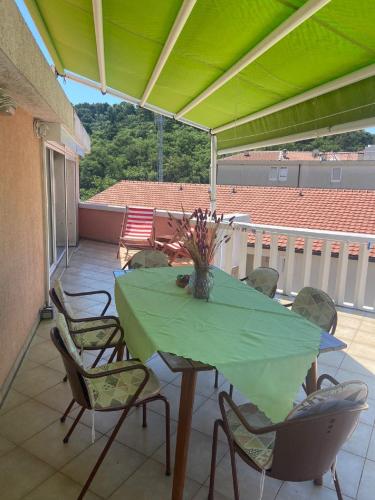 a table and chairs on a patio with a green umbrella at Beautiful Loft in Petrovac na Moru