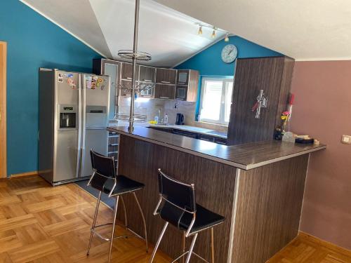 a kitchen with a counter with chairs and a refrigerator at Beautiful Loft in Petrovac na Moru
