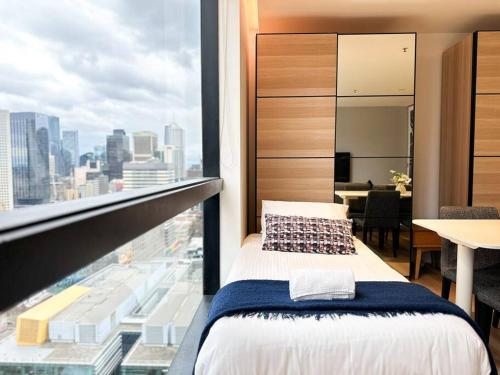 una camera da letto con una grande finestra con vista sulla città di Stylish Urban Retreat in Melbourne CBD a Melbourne