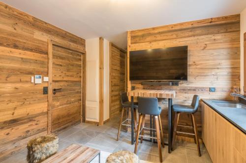 - une cuisine avec des murs en bois et un bar avec des tabourets dans l'établissement Studio Arbois - Welkeys, à Megève