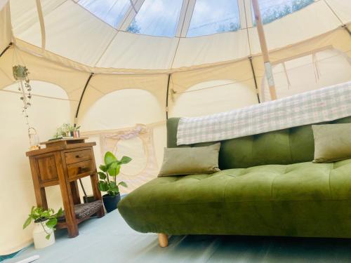 a living room with a green couch in a tent at Luxury Stargazing Glamping - Seren Aur with Hot Tub in Llanidloes
