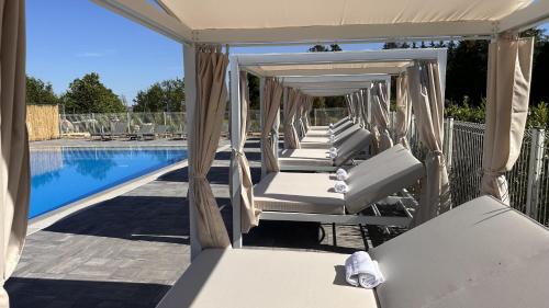 - une rangée de chaises longues blanches à côté de la piscine dans l'établissement Domaine du parc, à Grandvillers