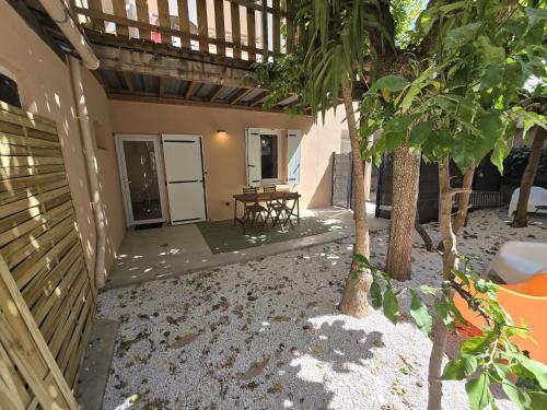 une vue extérieure d'une maison avec une table et des arbres dans l'établissement Gregbnb - T2 37m2 - Terrasse - Clim - Ouest - 3, à Toulon