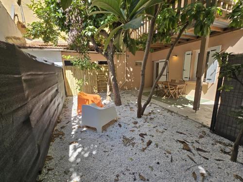 une chaise blanche assise dans une cour avec des arbres dans l'établissement Gregbnb - T2 37m2 - Terrasse - Clim - Ouest - 3, à Toulon