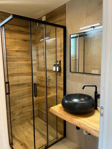 a bathroom with a glass shower with a black oar on a wooden shelf at Villa Giulietta lake view Jacuzzi Spa 108 in Blevio