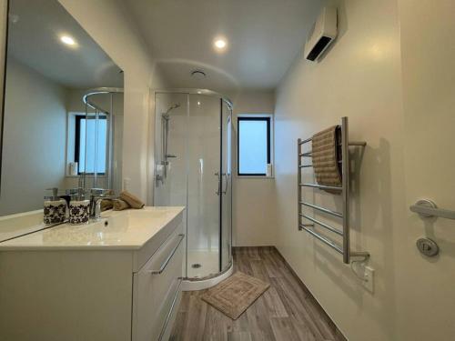 a white bathroom with a shower and a sink at CBD Luxury Parkside Living 2 Bedroom With Parking in Christchurch
