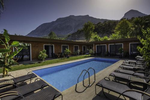a swimming pool with chairs and mountains in the background at Terra Garden Hotel in Kemer