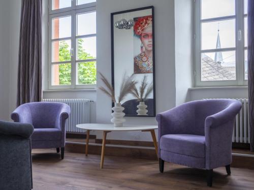 a living room with two chairs and a table with a vase at Hotel Lekker in Neumagen-Dhron