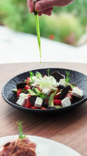 a person is preparing a salad in a black plate at Mykonos Earth Suites in Mýkonos City
