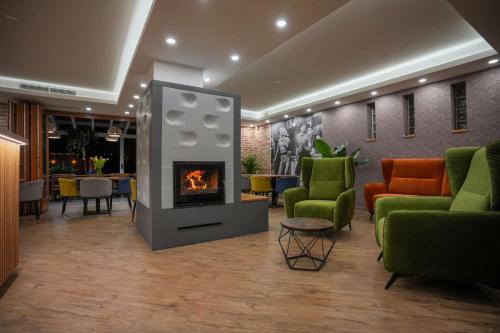 a lobby with a fireplace and chairs and tables at ChaChaCha House Vendégház in Egerszalók
